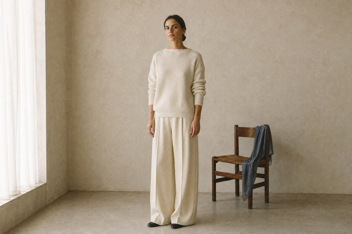 A woman in an ivory knit and cream wide trousers in a calm daylit studio corner